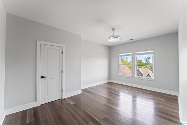 unfurnished room with visible vents, baseboards, and dark wood finished floors