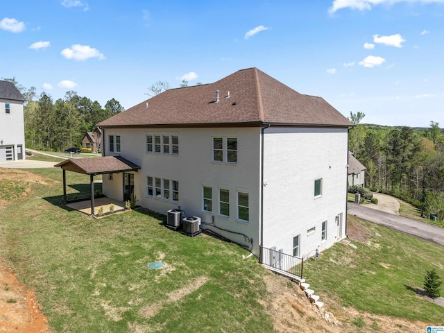 back of house featuring a yard, a shingled roof, a patio, and central air condition unit