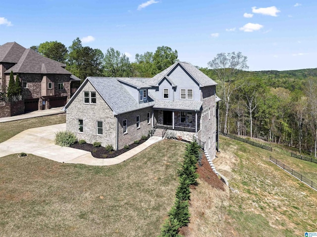 view of front facade featuring stone siding, fence, a front lawn, and covered porch