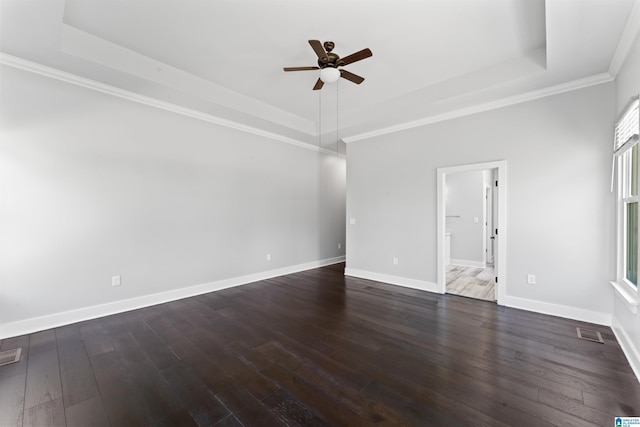 spare room featuring a tray ceiling, dark wood-style floors, baseboards, and a ceiling fan