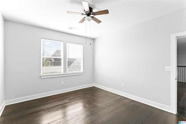 unfurnished room with a ceiling fan, baseboards, dark wood finished floors, and visible vents