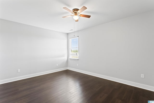 spare room featuring dark wood-style floors, baseboards, visible vents, and ceiling fan