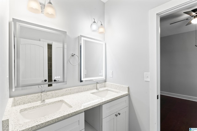 bathroom with double vanity, baseboards, a sink, and a ceiling fan