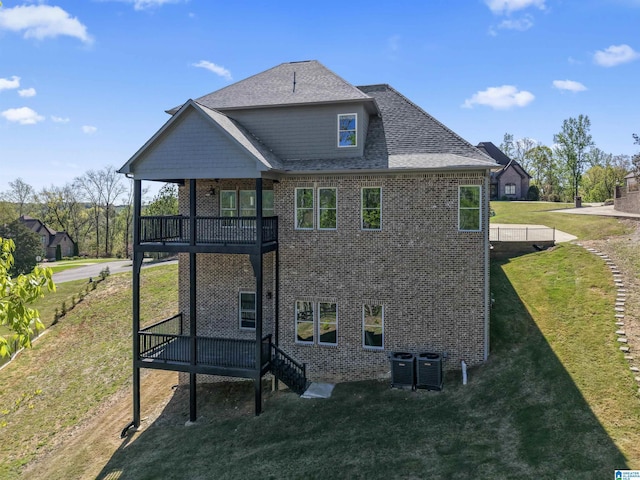 back of property with brick siding, central AC, and a lawn