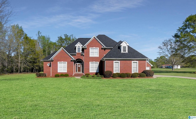 view of front of property with roof with shingles, brick siding, and a front lawn