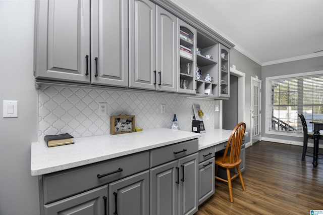 kitchen featuring dark wood-style flooring, baseboards, gray cabinets, glass insert cabinets, and crown molding
