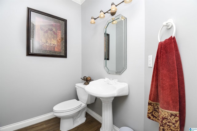 half bathroom featuring toilet, wood finished floors, and baseboards