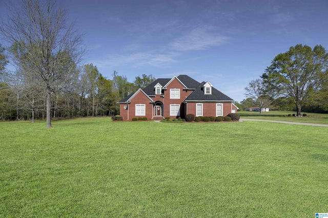 view of front of property with roof with shingles, brick siding, and a front lawn
