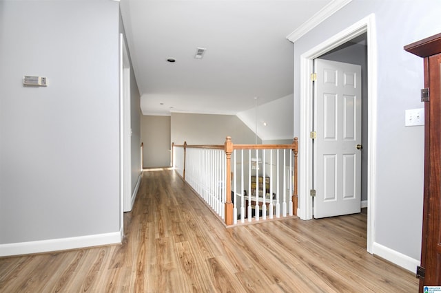 hallway featuring light wood-style floors, crown molding, and an upstairs landing