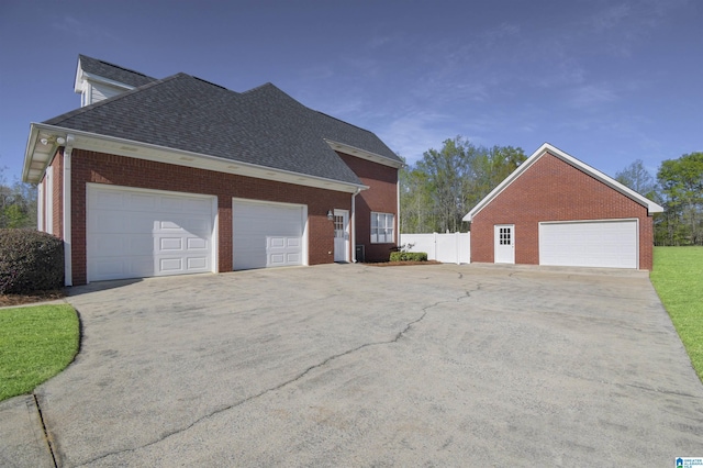 view of side of home featuring roof with shingles, brick siding, and fence
