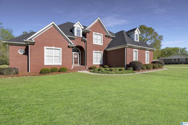 traditional home with roof with shingles, a front yard, and brick siding