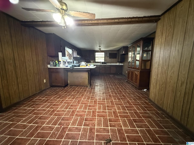 kitchen with wood walls, a peninsula, brick floor, and a ceiling fan