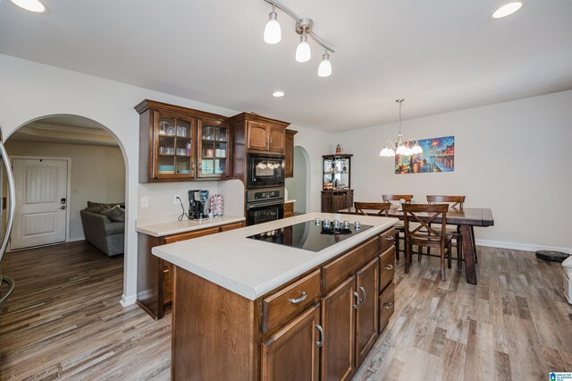 12723 Oak Forest Dr, Lake View, AL 35111 - kitchen with light wood-style flooring, arched walkways, light countertops, and black appliances