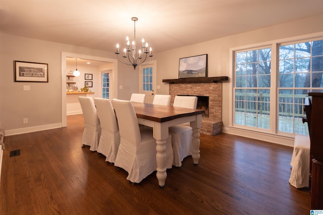 dining area featuring a notable chandelier, baseboards, a fireplace, visible vents, and dark wood finished floors
