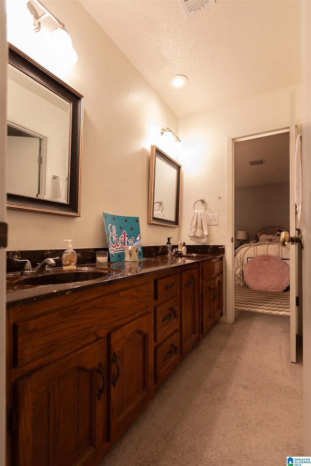 bathroom with a sink, double vanity, ensuite bath, and a textured ceiling