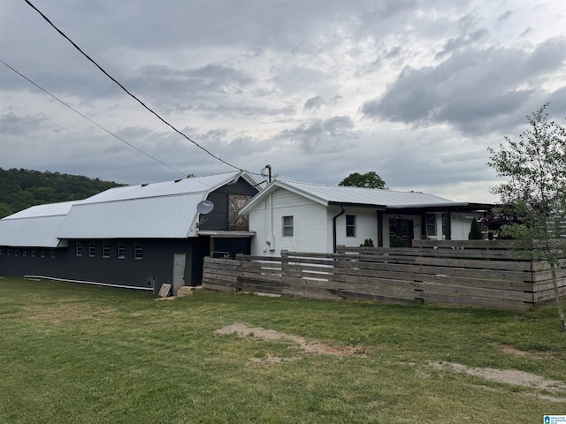 exterior space with fence, metal roof, and a front yard