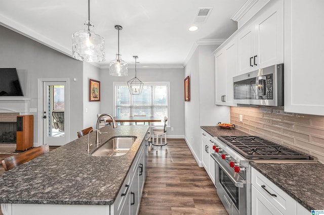 kitchen with visible vents, a kitchen island with sink, a sink, stainless steel appliances, and backsplash