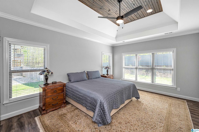 bedroom featuring a tray ceiling, wood finished floors, multiple windows, and visible vents