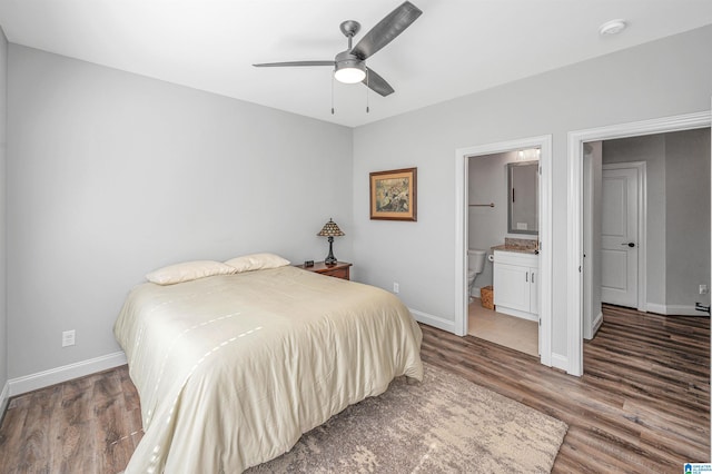 bedroom with ensuite bathroom, baseboards, and wood finished floors