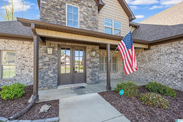 entrance to property with roof with shingles, french doors, and stone siding