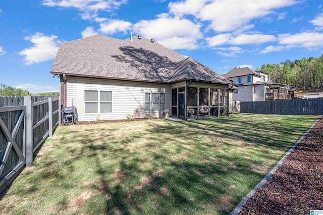 back of property featuring a yard, roof with shingles, a fenced backyard, and a sunroom