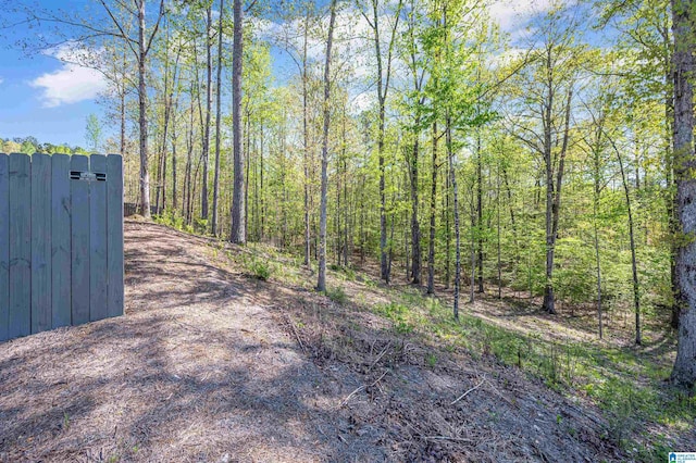 view of street featuring a wooded view, driveway, and a gate