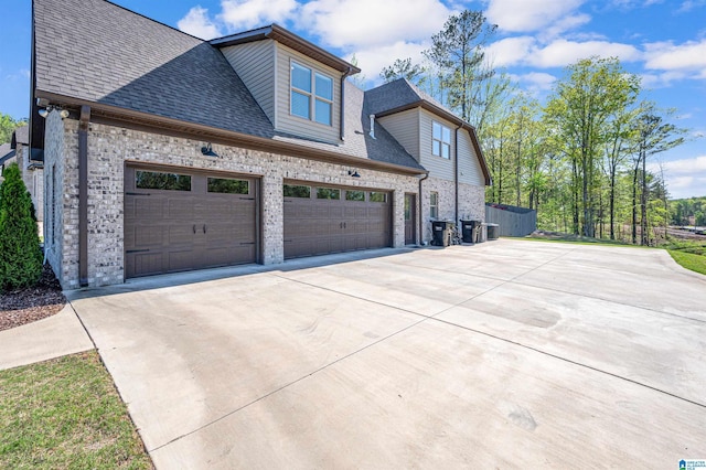 view of property exterior with roof with shingles, driveway, and brick siding