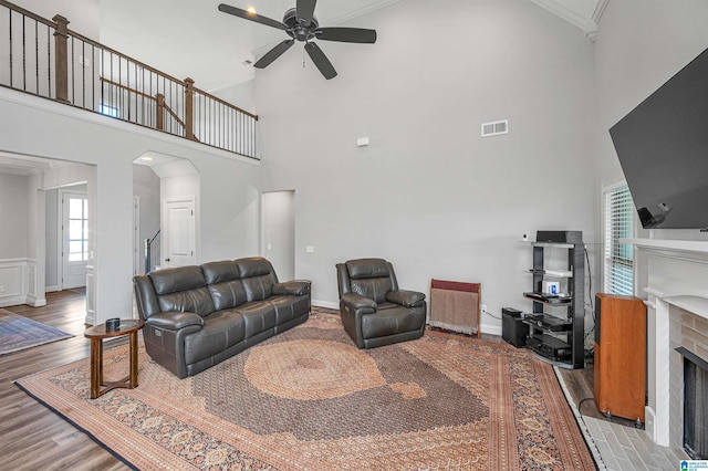 living area featuring high vaulted ceiling, a fireplace, arched walkways, a ceiling fan, and visible vents