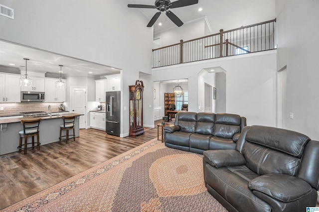living area featuring crown molding, arched walkways, a ceiling fan, recessed lighting, and dark wood-style floors
