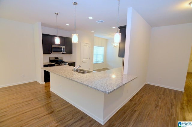 kitchen with appliances with stainless steel finishes, wood finished floors, a sink, and visible vents