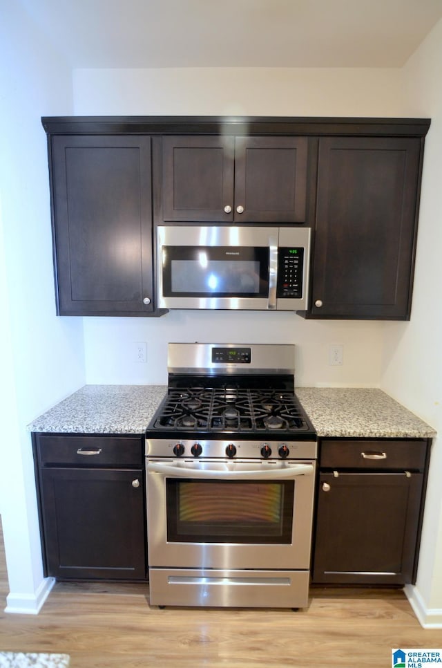 kitchen featuring light wood-type flooring, baseboards, dark brown cabinets, and appliances with stainless steel finishes