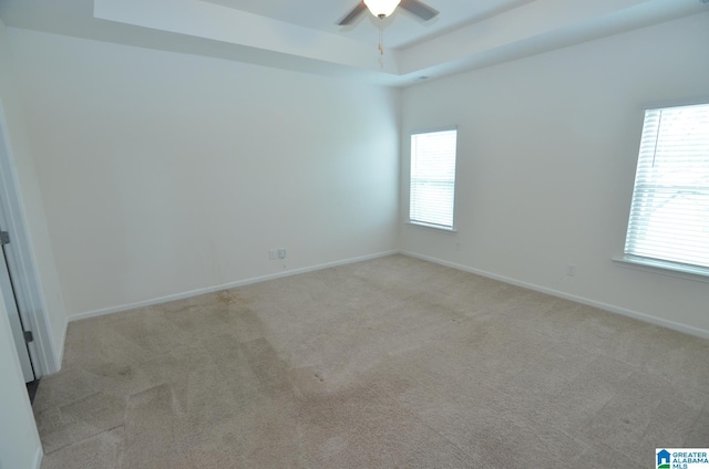 empty room featuring carpet floors, a ceiling fan, and a tray ceiling