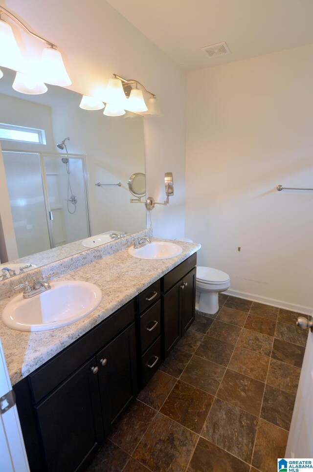 full bathroom with stone tile flooring, a sink, double vanity, and a stall shower
