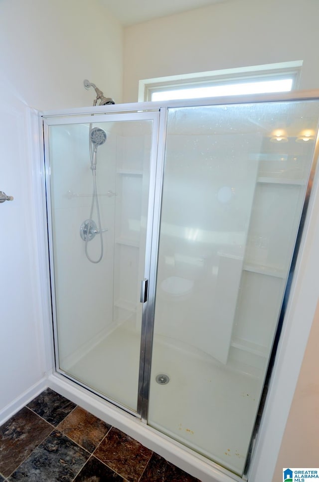 bathroom featuring stone finish flooring and a stall shower