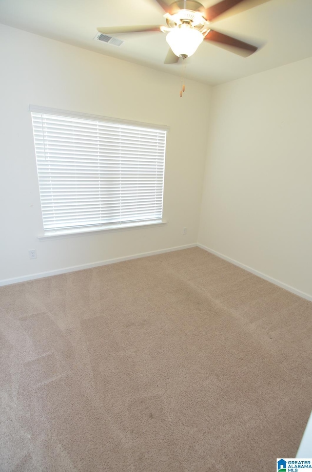 unfurnished room with carpet flooring, visible vents, a ceiling fan, and baseboards
