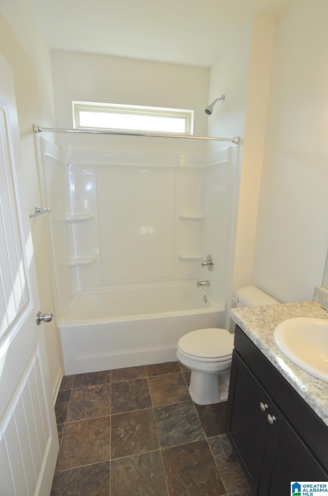 full bath with toilet, stone finish floor, vanity, and shower / tub combination