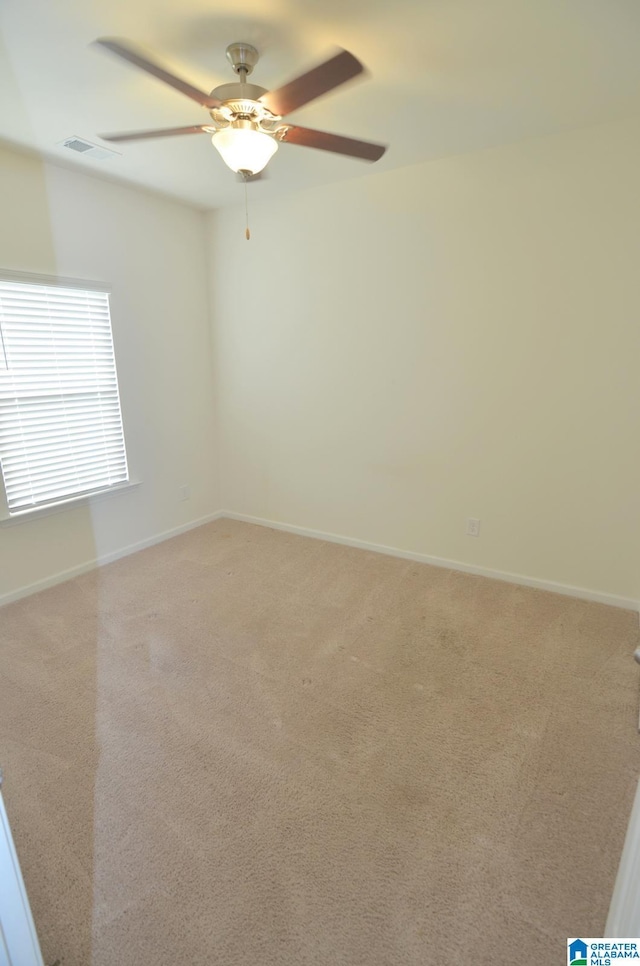 empty room with ceiling fan, visible vents, baseboards, and light carpet