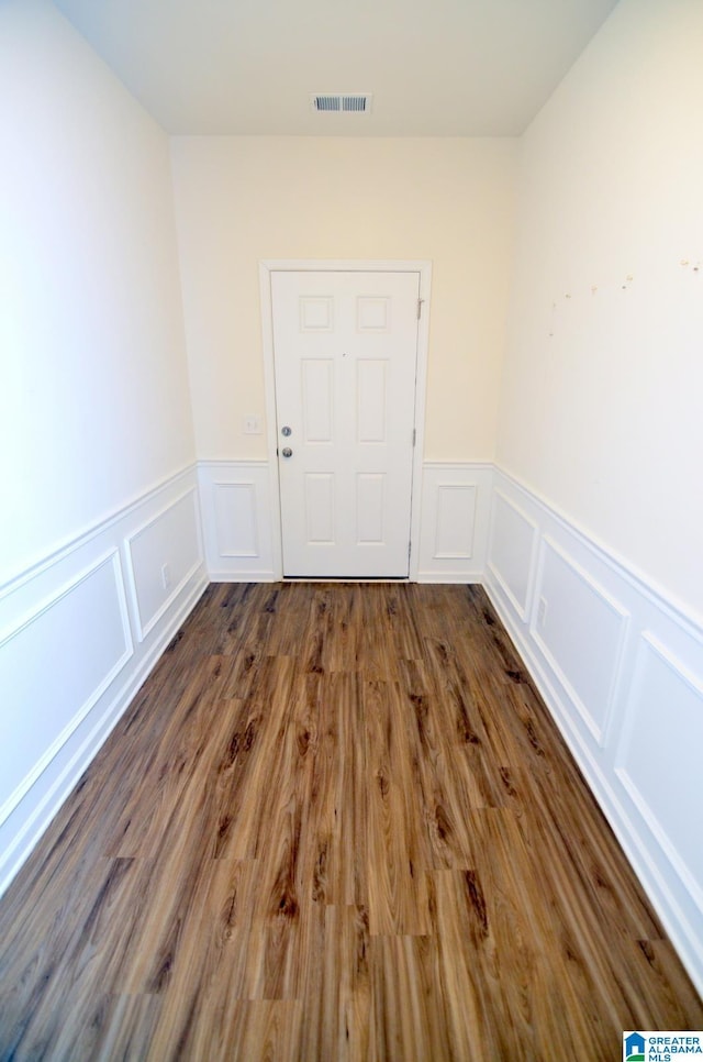 unfurnished room with wainscoting, a decorative wall, and visible vents