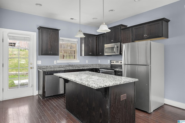 kitchen with dark wood-type flooring, a center island, appliances with stainless steel finishes, and plenty of natural light