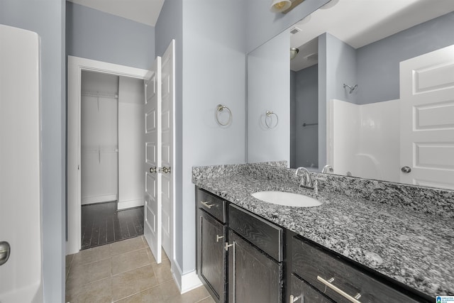 bathroom featuring tile patterned floors, vanity, baseboards, and walk in shower