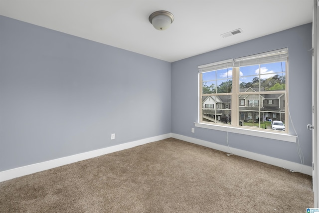 carpeted spare room featuring visible vents and baseboards
