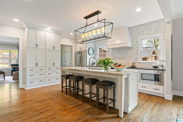 1119 Crest Ave, Homewood, AL 35209 - kitchen with custom exhaust hood, a sink, appliances with stainless steel finishes, an island with sink, and a breakfast bar area