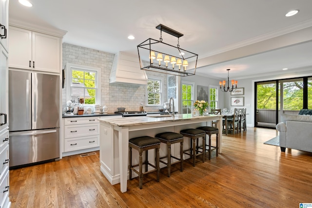 1119 Crest Ave, Homewood, AL 35209 - kitchen featuring custom exhaust hood, tasteful backsplash, a chandelier, light wood finished floors, and stainless steel refrigerator