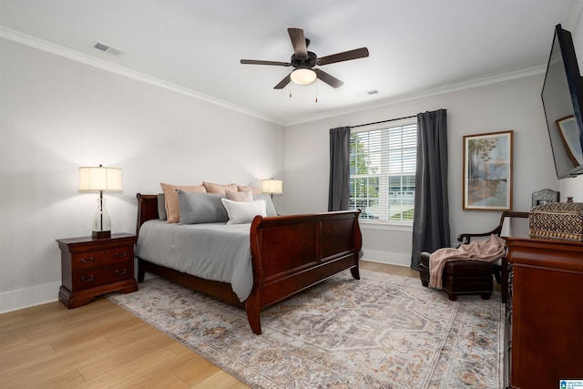 bedroom with light wood-style floors, crown molding, baseboards, and visible vents