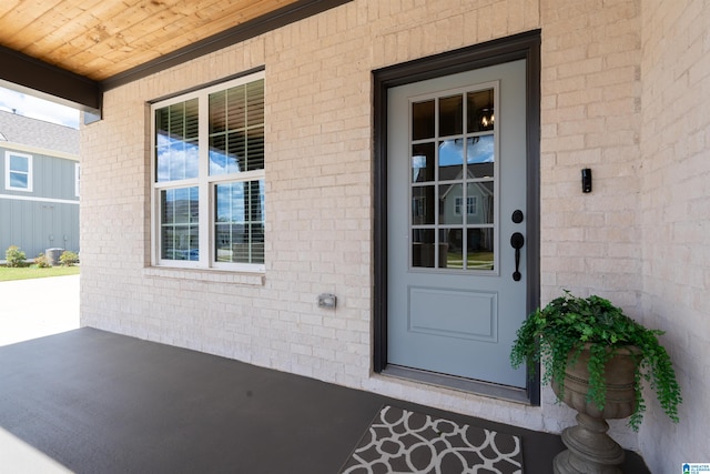entrance to property featuring a porch and brick siding