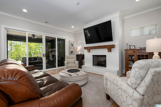 living room featuring a fireplace, ornamental molding, visible vents, recessed lighting, and wood finished floors