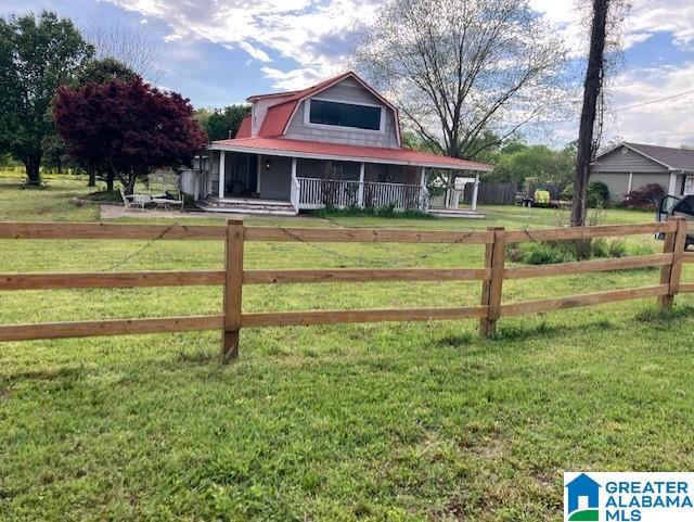 farmhouse inspired home with a porch, a front lawn, and a fenced front yard