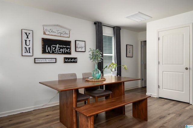 dining room featuring visible vents, baseboards, and wood finished floors