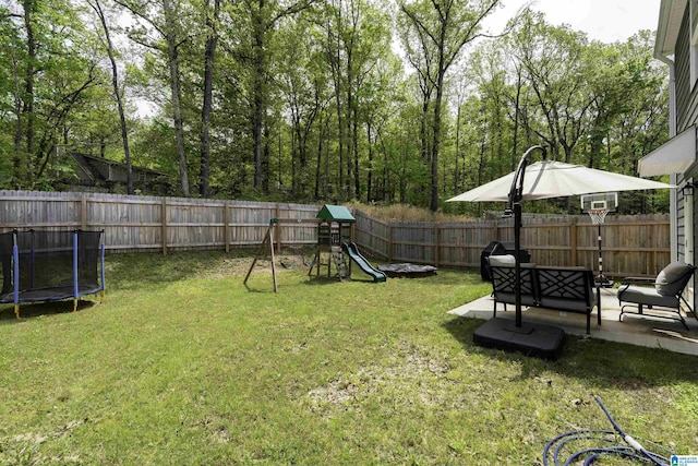 view of yard with a trampoline, a patio area, a fenced backyard, and a playground
