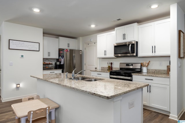 kitchen featuring white cabinetry, a kitchen island with sink, a sink, stainless steel appliances, and dark wood-style floors